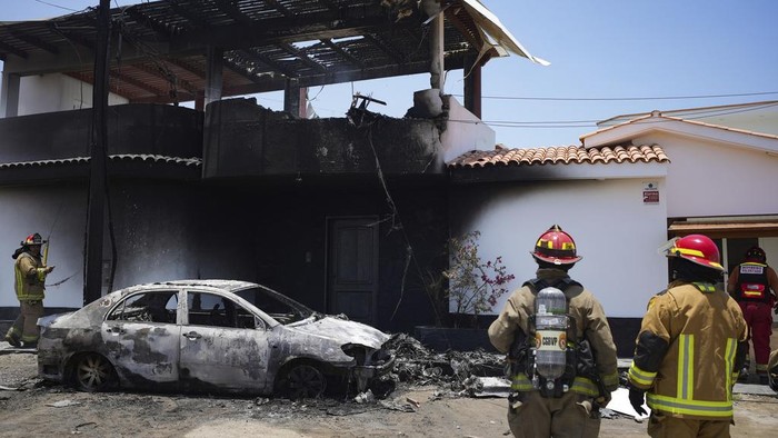 Firefighters work around the site where a small plane crashed into a residence in the San Bartolo district of Lima, Peru, Saturday, Feb. 22, 2025. According to police, the pilot and copilot were rescued and taken to the nearest hospital.  No other injuries were reported. (AP Photo/Guadalupe Pardo)