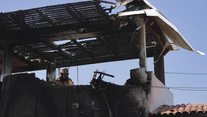 Firefighters work around the site where a small plane crashed into a residence in the San Bartolo district of Lima, Peru, Saturday, Feb. 22, 2025. According to police, the pilot and copilot were rescued and taken to the nearest hospital.  No other injuries were reported. (AP Photo/Guadalupe Pardo)