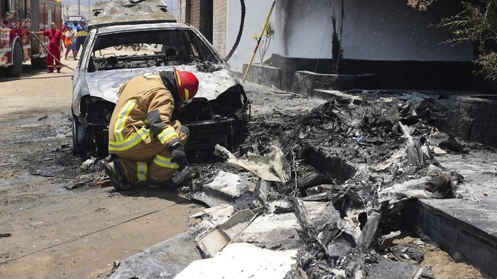Firefighters work around the site where a small plane crashed into a residence in the San Bartolo district of Lima, Peru, Saturday, Feb. 22, 2025. According to police, the pilot and copilot were rescued and taken to the nearest hospital.  No other injuries were reported. (AP Photo/Guadalupe Pardo)