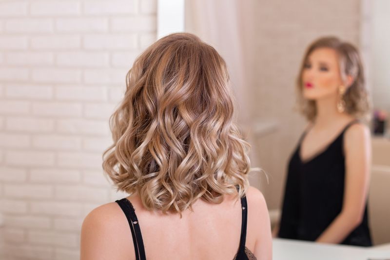 Female back with short, curly, natural blonde hair in hairdressing salon