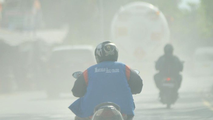 Pengendara melintas di antara debu yang beterbangan di Jalan Raya Indarung, Padang, Sumatera Barat, Selasa (25/2/2025). Debu akibat tumpahan material dari truk pengangkut hasil pertambangan itu mengganggu pengendara yang melintas. ANTARA FOTO/Iggoy el Fitra/YU