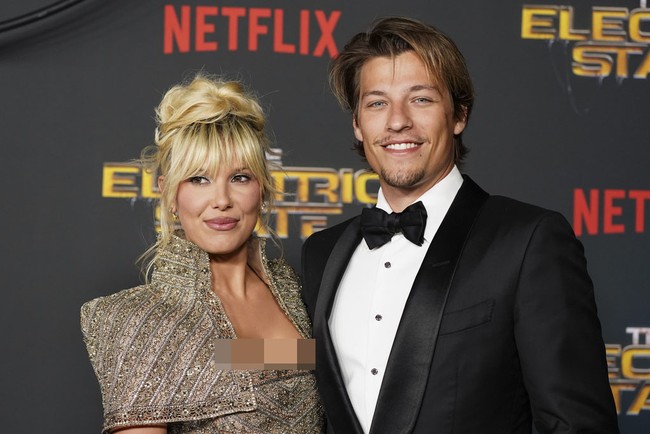 Sang suami, Jake Bongiovi, tampil gagah dalam tuxedo hitam klasik dengan kemeja putih dan dasi kupu-kupu. Paduan ini memberikan look yang timeless dan semakin menonjolkan kontras dengan gaun Millie yang berkilauan. Foto: Jordan Strauss/Invision/AP