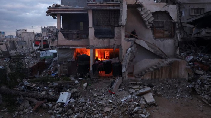 Palestinians gather around a fire, amid a ceasefire between Israel and Hamas, in Khan Younis, in the southern Gaza Strip, February 24, 2025. REUTERS/Ramadan Abed