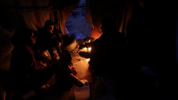 Potret Warga Khan Younis Tinggal di Rumah-rumah yang Hancur Palestinians gather around a fire, amid a ceasefire between Israel and Hamas, in Khan Younis, in the southern Gaza Strip, February 24, 2025. REUTERS/Ramadan Abed