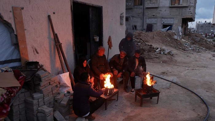 Palestinians gather around a fire, amid a ceasefire between Israel and Hamas, in Khan Younis, in the southern Gaza Strip, February 24, 2025. REUTERS/Ramadan Abed