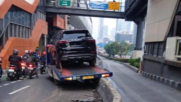 Truk towing yang mengangkut mobil Chery berwarna hitam menabrak pembatas jalan di Jalan MT Haryono, Jaksel. (media sosial X @tmcpoldametro)