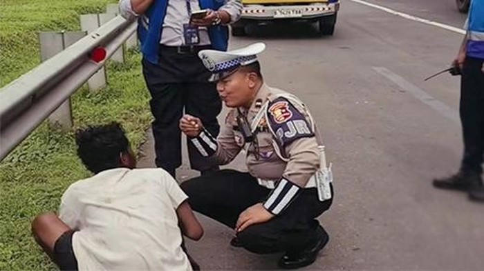Anggota Patroli Jalan Raya (PJR) Cikampek, Aipda Agus Salim, menyelamatkan seorang pria yang hampir terlindas di Jalan Tol Jakarta-Cikampek. Foto: Dok. Situs Korlantas Polri.