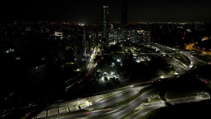 A police officer stops a driver at a checkpoint during curfew due to a nationwide blackout in Santiago, Chile, Tuesday, Feb. 25, 2025. (AP Photo/Matias Basualdo)