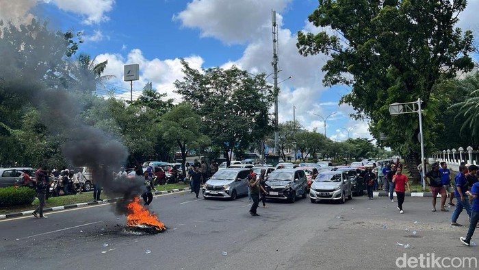 Driver online menggelar aksi demonstrasi di depan Kantor Gubernur Sulsel dengan membakar ban di tengah jalan, Rabu (26/2/2025).