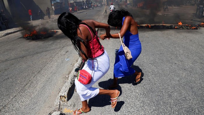 Haiti Mencekam Saat Geng Bersenjata Serang Kawasan Ibu Kota Women run past burning street barricades in the Solino district as residents call for help from the government and protest the lack of security, in Port-au-Prince, Haiti February 20, 2025 REUTERS/Ralph Tedy Erol TPX IMAGES OF THE DAY