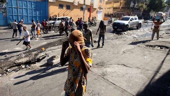Haiti Mencekam Saat Geng Bersenjata Serang Kawasan Ibu Kota People walk on a street after civilians and members of the National Police clashed with gangs, in Port-au-Prince, Haiti February 23, 2025. REUTERS/Fildor Pq Egeder