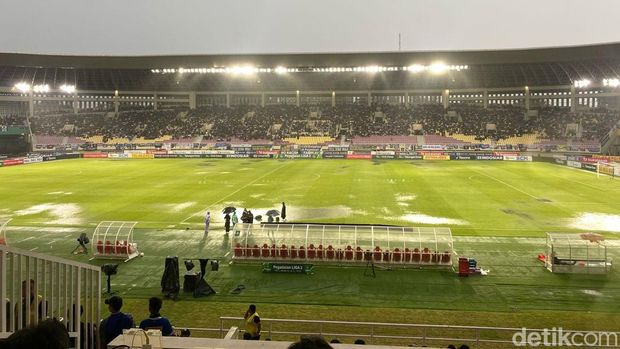 Ofisial tampak berusaha mengeringkan lapangan Stadion Manahan yang tergenang di tengah laga final Liga 2 antara PSIM Jogja versus Bhayangkara FC, Rabu (26/2/2025).