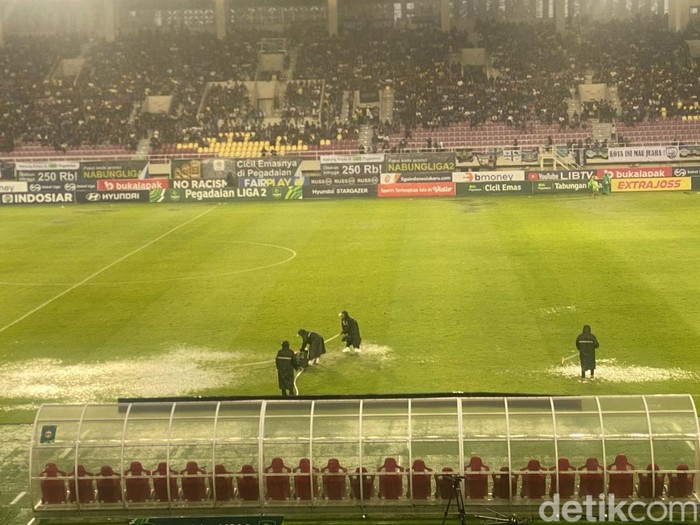 Ofisial tampak berusaha mengeringkan lapangan Stadion Manahan yang tergenang di tengah laga final Liga 2 antara PSIM Jogja versus Bhayangkara FC, Rabu (26/2/2025).