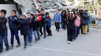 Anak-anak Palestina mengantre di sekolah yang rusak, di tengah gencatan senjata antara Israel dan Hamas, di Kota Gaza, 25 Februari 2025.  