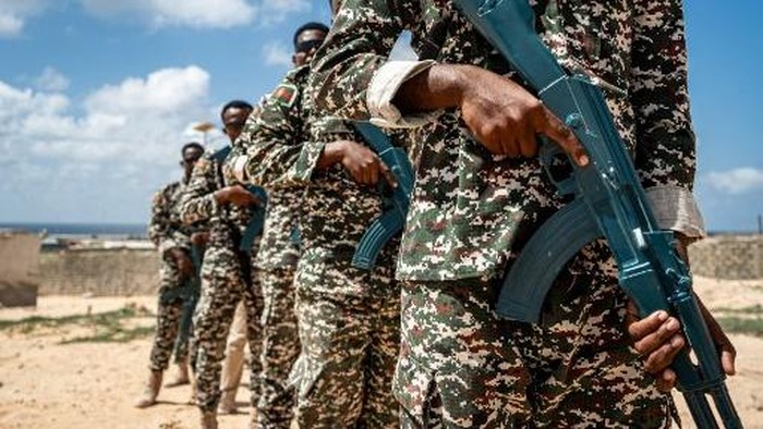 Troops taking part in the Somali Army Cadet Officers Course (SOCAC) brandish their practice weapons before a military drill at the General Dhagabadan Training Centre in Mogadishu on March 19, 2024. European Union Training Mission in Somalia (EUTM-S) trainers instruct on a regular basis Somali soldiers on a range of topics, including urban combat, explosive devices detection and disposal, and protective engineering techniques. (Photo by Amaury Falt-Brown / AFP)