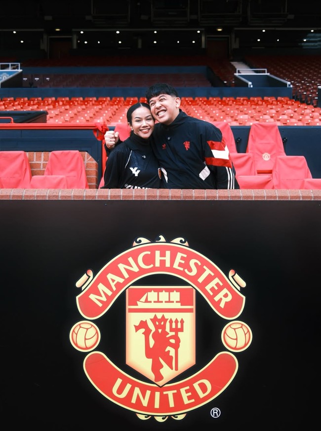 Berpose bersama di Old Trafford Stadium, Yura dan suaminya pamer senyum sumringah mereka. Keduanya juga kompak dengan busana bernuansa hitam. Foto: Instagram/@yurayunita