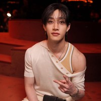 Personel grup KPop Stray Kids itu tampil dengan gaya kasual dan busana Fendi serba krem. Bang Chan mengenakan off shoulder cardigan, loose pants, dan sneakers. Atasannya memiliki detail kancing menyamping yang dibiarkan terbuka, mengekspos tanktop dan bahu bidangnya. Foto: Getty Images