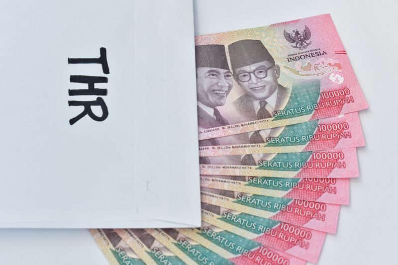 Indonesian Money, rupiah or IDR in envelope with THR Text. The THR envelope contains IDR 100,000 in cash. THR is a holiday allowance on Eid al-Fitr or Eid al-Fitr. space for text, white background.