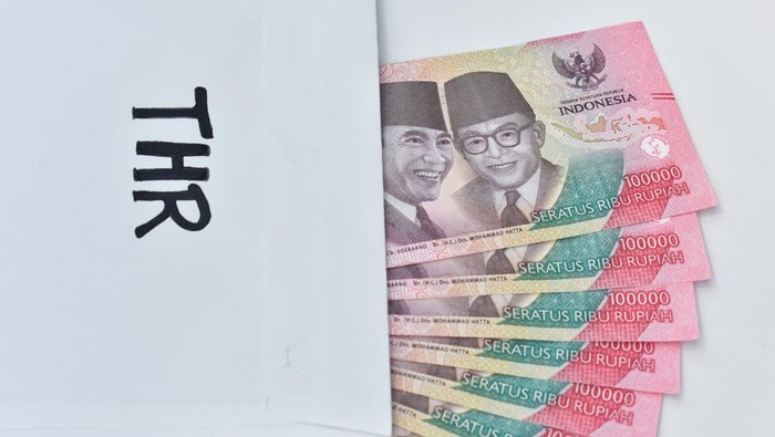 Indonesian Money, rupiah or IDR in envelope with THR Text. The THR envelope contains IDR 100,000 in cash. THR is a holiday allowance on Eid al-Fitr or Eid al-Fitr. space for text, white background.