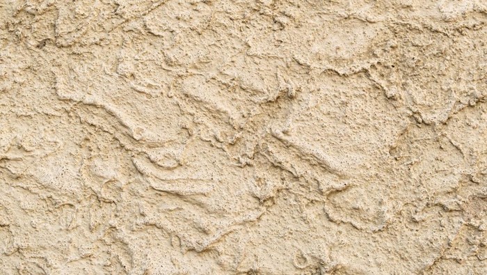 Yellow plaster on the wall in rough style, sandy texture, used as an exterior facade finish. texture of building materials