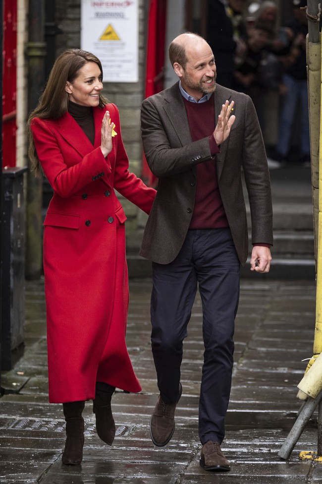 Dalam kunjungan tersebut, Kate yang bergelar Putri Wales mengenakan mantel khusus rancangan Alexander McQueen berwarna merah terang, yang dikenal sebagai Welsh Red. Warna ini merujuk pada salah satu warna dalam bendera nasional Wales, yang terdiri dari hijau, putih, dan gambar naga merah. Middleton juga menyematkan bunga daffodil di kerah mantelnya, simbol nasional Wales.  (Foto: Aaron Chown/PA via AP)