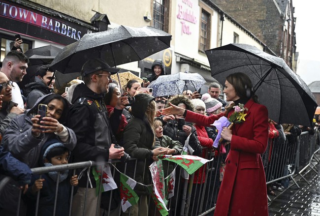 Saat berjalan di sekitar kota, Middleton melepas mantelnya, memperlihatkan busana lainnya. Ia mengenakan turtleneck hitam yang dipadukan dengan jaket hijau zaitun serta rok lipit motif kotak dari Gucci.  (Foto: Ben Stansall/Pool Photo via AP)