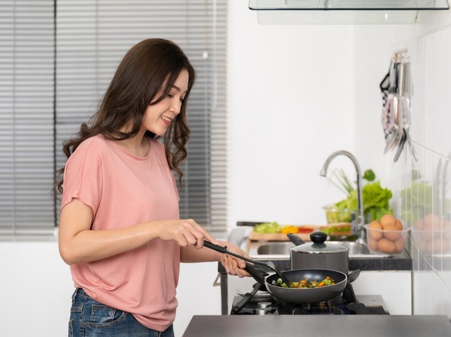 happy young woman cooking and preparing food in the kitchen at home