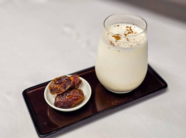 Dates and date smoothie with cinnamon powder on the top and serve with rectangular tray.