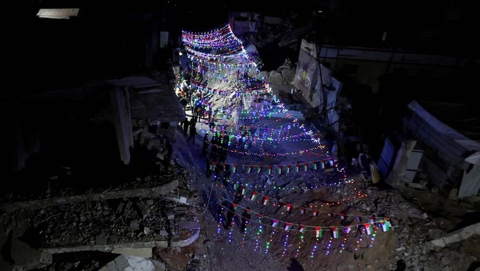 ISRAEL-PALESTINIANS/GAZA-RAMADAN A Palestinian walks past graffiti and the rubble of buildings, ahead of the holy fasting month of Ramadan, amid a ceasefire between Israel and Hamas, in Khan Younis, in the southern Gaza Strip, February 27, 2025. REUTERS/Ramadan Abed