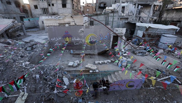 A Palestinian walks past graffiti and the rubble of buildings, ahead of the holy fasting month of Ramadan, amid a ceasefire between Israel and Hamas, in Khan Younis, in the southern Gaza Strip, February 27, 2025. REUTERS/Ramadan Abed
