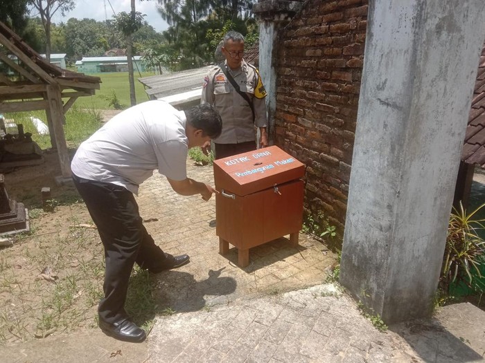 Personil kepolisian mengecek kondisi kotak amal di area pemakaman wilayah Banyunganti Lor, Kaliagung, Sentolo, Kulon Progo, Kamis (27/2/2025).
