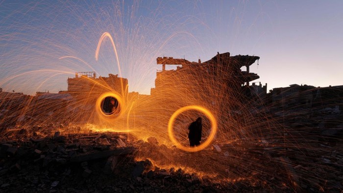 Palestinians spin steel wool sparklers amid the rubble of buildings, ahead of the holy fasting month of Ramadan, amid a ceasefire between Israel and Hamas, at Jabalia refugee camp, northern Gaza Strip, February 28, 2025. REUTERS/Mahmoud Issa     TPX IMAGES OF THE DAY
