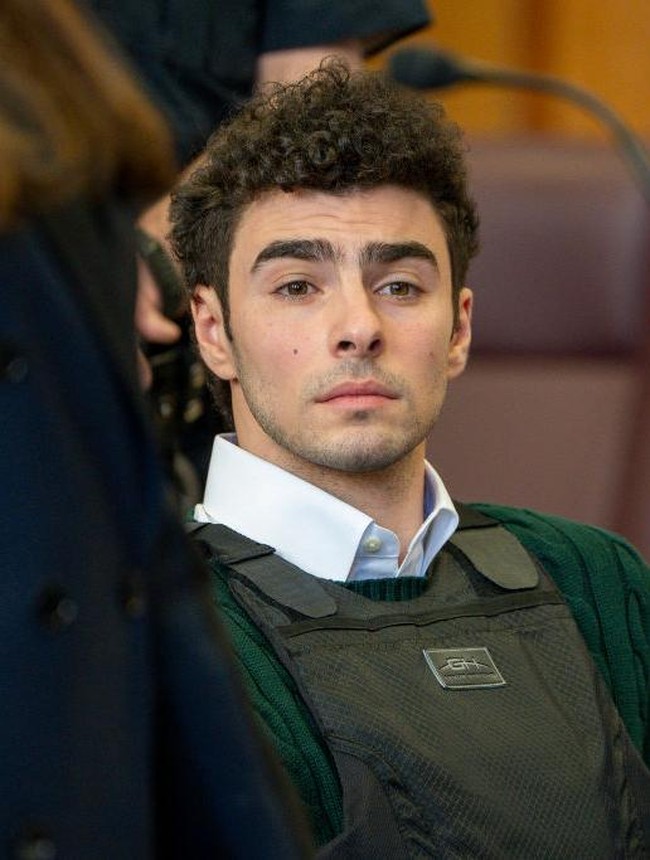 Dalam persidangan terbarunya, Luigi tampil mengenakan sweater rajut berwarna hijau, celana khaki, dan sepatu loafers cokelat tanpa kaus kaki. Meskipun mengenakan rompi anti-peluru dan borgol di pergelangan tangan serta kaki, penampilannya tetap dianggap modis oleh para penggemarnya.  Foto: Getty Images/Pool