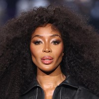 Untuk makeup, Naomi tampil dengan smokey eyes bernuansa cokelat yang tajam, serta contouring di pipi yang menonjolkan struktur wajahnya. Look ini semakin memperkuat aura fierce yang khas dari seorang supermodel asal Inggris ini. Foto: Getty Images/Estrop
