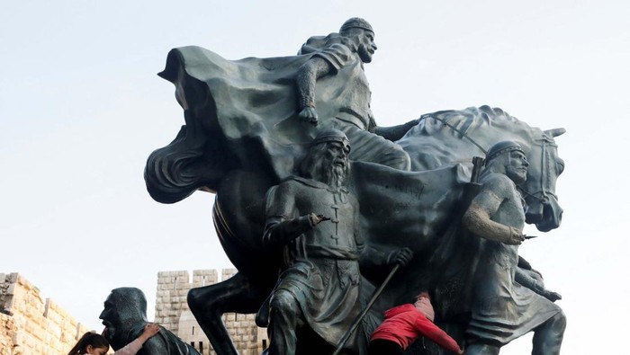 Children climb the Salah Al Din Statue in Damascus, Syria, February 27, 2025. REUTERS/Mahmoud Hassano