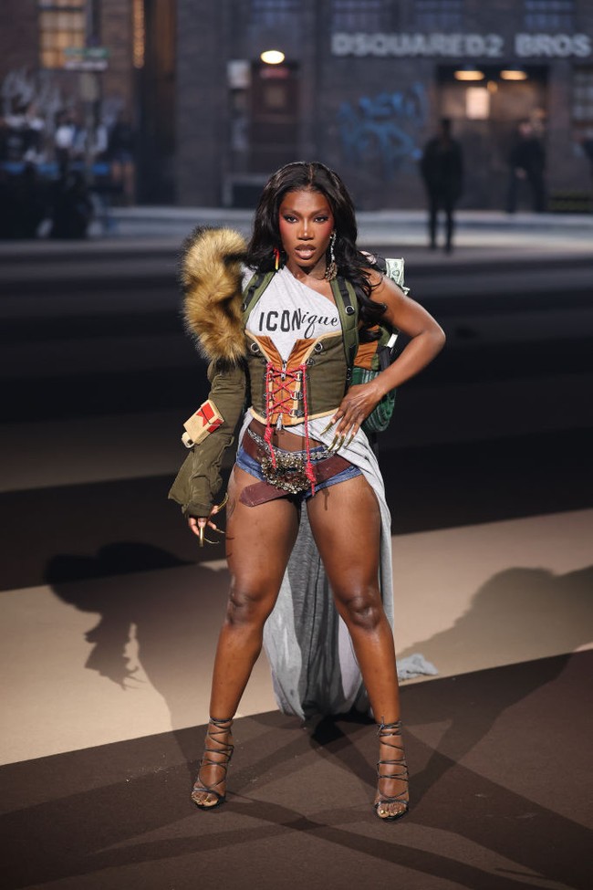Atasan bertulisan Iconique dan berekor panjang yang menjuntai itu dibungkus korset hijau dan jaket parka senada. Sabuk besar ikut menambah efek dramatis. (Foto: Daniele Venturelli/WireImage)