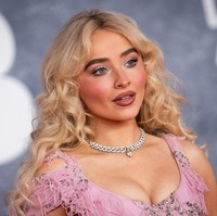 Tata rias Carpenter pun tak kalah menawan. Ia tampil dengan riasan mata shimmer berwarna krem, alis tebal yang tegas, pipi merona, serta lipstik oranye tua yang menambah kesan dramatis. Rambut pirangnya ditata bergelombang dan dibiarkan tergerai melewati bahunya, menciptakan tampilan klasik nan elegan. (Foto: Scott Garfitt/Invision/AP)