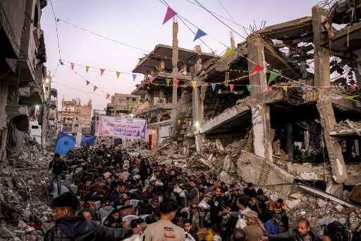 People gather for the iftar, or fast-breaking meal, on the first day of the Muslim holy fasting month of Ramadan in Jabalia in the northern Gaza Strip on March 1, 2025 by the rubble of collapsed buildings that were destroyed during the war between Israel and Hamas, amid the ongoing truce. (Photo by Bashar TALEB / AFP)