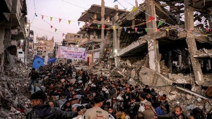 People gather for the iftar, or fast-breaking meal, on the first day of the Muslim holy fasting month of Ramadan in Jabalia in the northern Gaza Strip on March 1, 2025 by the rubble of collapsed buildings that were destroyed during the war between Israel and Hamas, amid the ongoing truce. (Photo by Bashar TALEB / AFP)