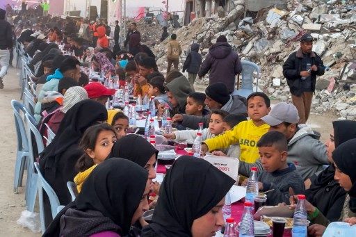 Palestinians gather for a communal iftar, or fast-breaking meal, on the first day of the Muslim holy month of Ramadan, amid building rubble in Rafah in the southern Gaza Strip on March 1, 2025. (Photo by AFP)