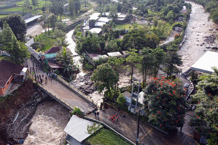 Warga melihat kondisi jembatan Ciliwung yang putus akibat meluapnya sungai Ciliwung di Desa Jogjogan, Cisarua, Kabupaten Bogor, Jawa Barat, Senin (3/3/2025). Hujan lebat yang mengguyur wilayah tersebut menyebabkan air sungai meluap dan mengakibatkan jembatan penghubung  Desa Jogjogan dan Desa Leuwimalang Kecamatan Cisarua, yang biasa digunakan warga untuk beraktivitas warga, putus tidak bisa dilewati. ANTARA FOTO/Yulius Satria Wijaya/YU