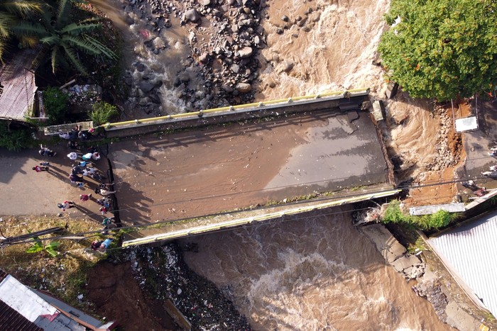 Warga melihat kondisi jembatan Ciliwung yang putus akibat meluapnya sungai Ciliwung di Desa Jogjogan, Cisarua, Kabupaten Bogor, Jawa Barat, Senin (3/3/2025). Hujan lebat yang mengguyur wilayah tersebut menyebabkan air sungai meluap dan mengakibatkan jembatan penghubung  Desa Jogjogan dan Desa Leuwimalang Kecamatan Cisarua, yang biasa digunakan warga untuk beraktivitas warga, putus tidak bisa dilewati. ANTARA FOTO/Yulius Satria Wijaya/YU