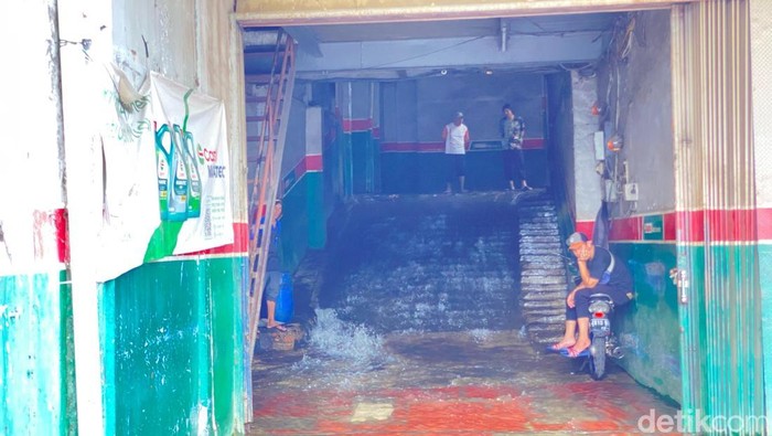 Lalu lintas di Jalan Margonda Raya arah Jakarta tersendat karena air yang menggenangi jalan. Luapan kali melewati bangunan bengkel bak air terjun. (Devi P/detikcom)