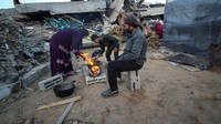 Mereka memasak di tunggu di antara reruntuhan bangunan akibat serangan Israel.  