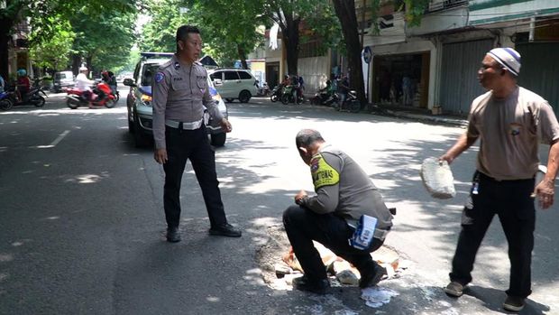 Polisi menambal lubang jalan di Jalur Pantura, Pasuruan.