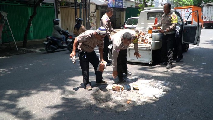 Polisi menambal lubang jalan di Jalur Pantura, Pasuruan.
