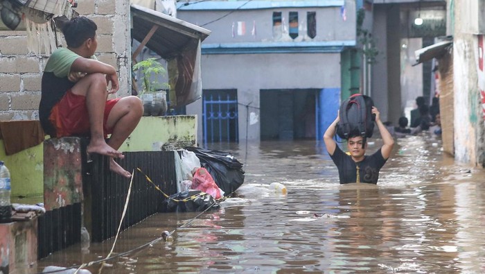 Warga berjalan melintasi banjir di kawasan Jalan Jembatan 1, Kramat Jati, Jakarta, Senin (3/3/2025). Kawasan di sepanjang aliran Kali Ciliwung tersebut terendem banjir setinggi 30 cm - 130 cm akibat luapan Bendungan Katulampa yang sudah mencapai siaga satu pada Minggu (2/3) malam. ANTARA FOTO/Asprilla Dwi Adha/YU