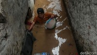 Tampak warga menerobos banjir sambil membawa ayam peliharaannya.