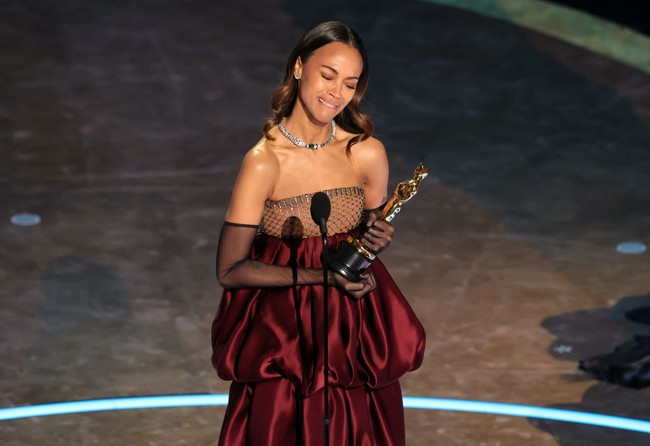 Saat naik ke atas panggung untuk menerima piala Oscars pertamanya, Zoe Saldana mencuri atensi dengan penampilannya yang glamor. Zoe mengenakan gaun yang dibuat khusus untuknya dari rumah mode Saint Laurent. Foto: Getty Images/Kevin Winter