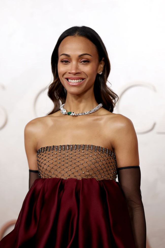 Seperti dikutip dari WWD, Zoe Saldana membawa tren bubble dress ke ajang Oscars 2025. Gaun strapless tersebut memiliki bustier semi transparan dengan detail berkilau dan benang hitam dalam pola berlian. Foto: Getty Images/Mike Coppola